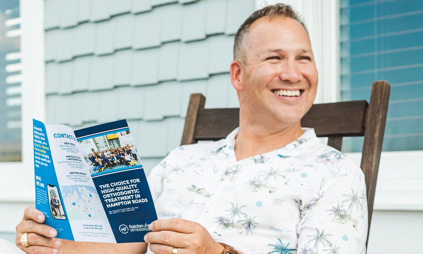 Man smiling and reading broacher of Invisalign Clear Aligners treatment